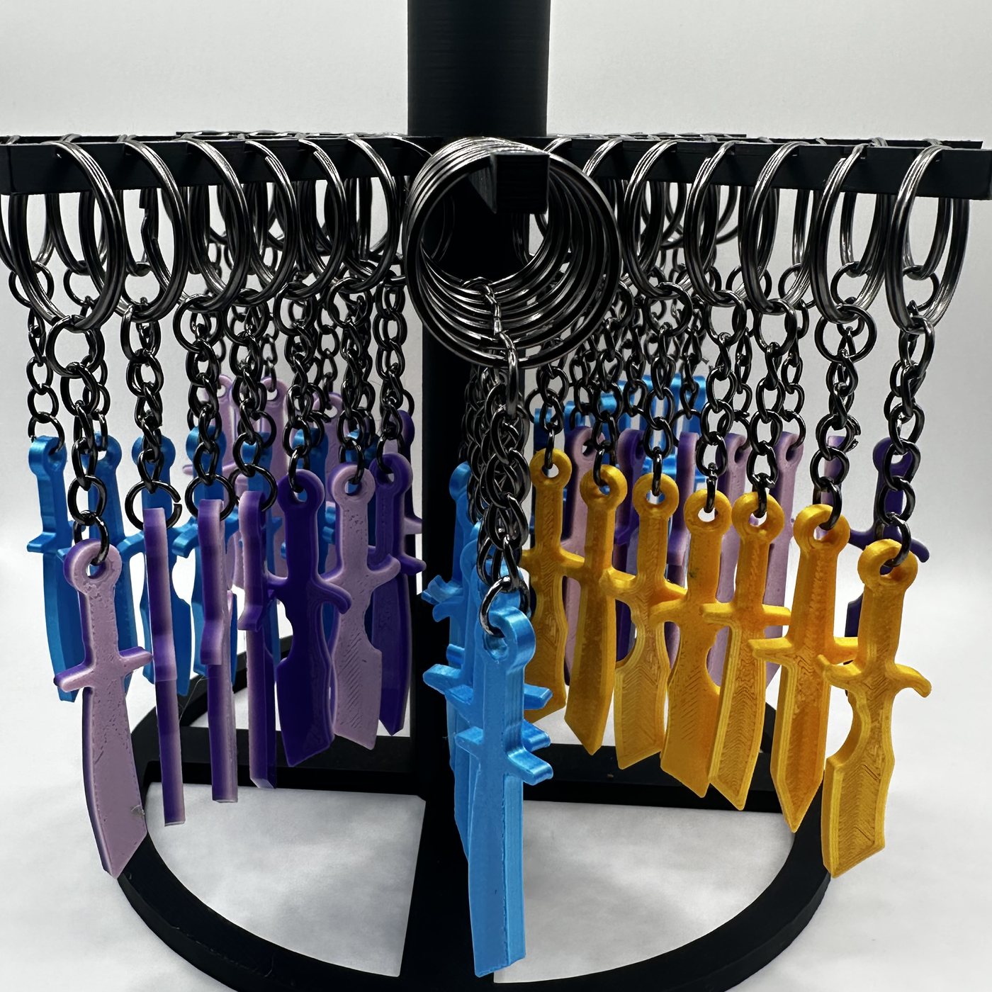 Mini throwing knife keychains in blue, purple and gold on a counter display rack